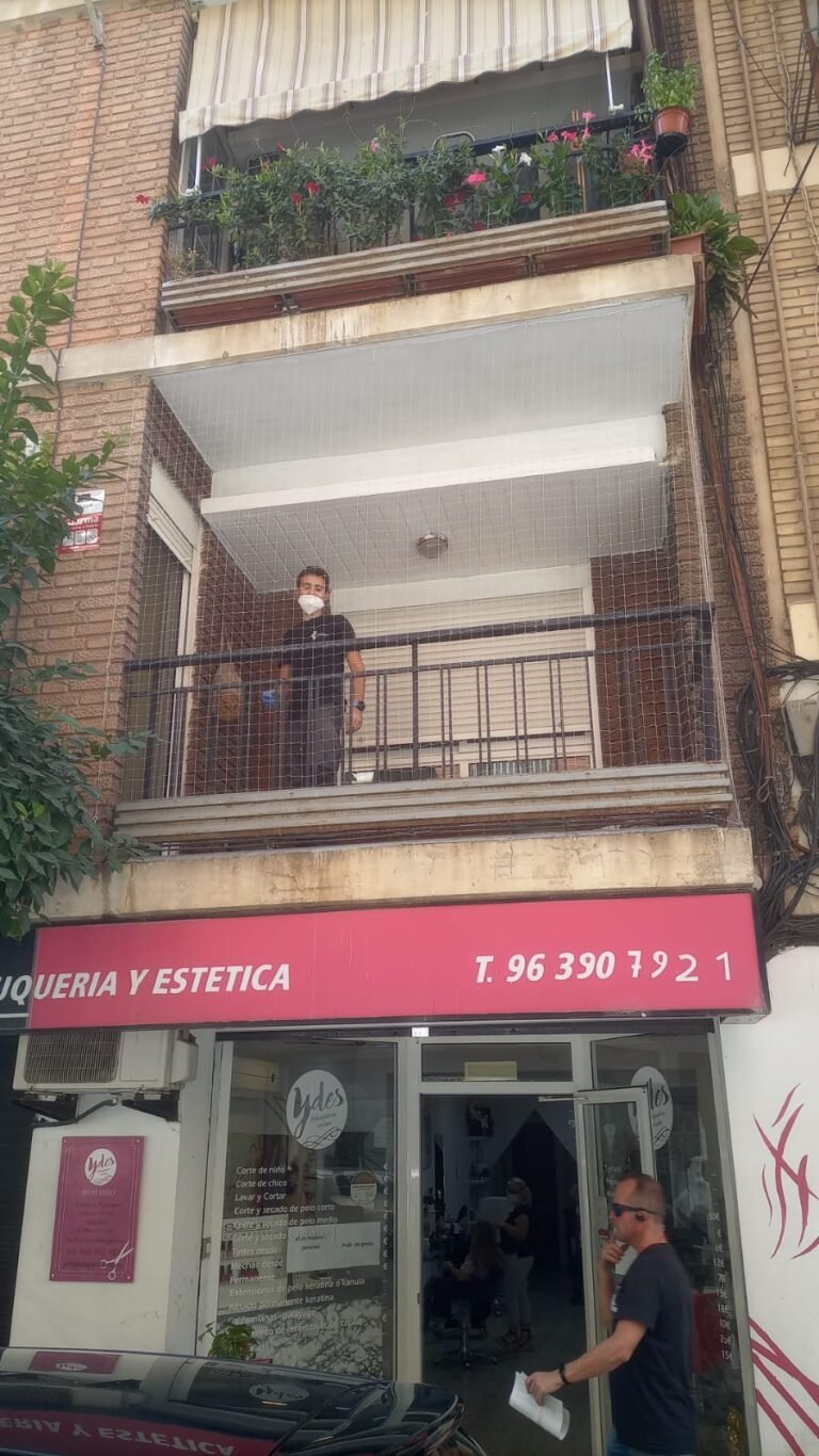Instalador trabajando en la red de un balcón en fachada
